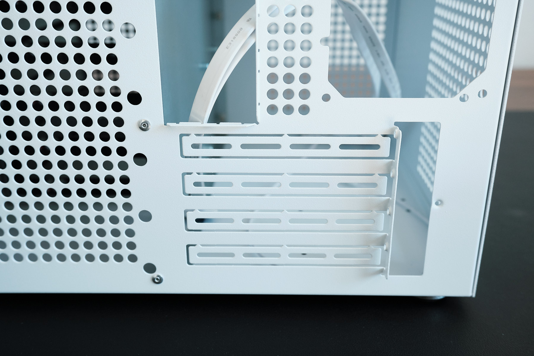 Rear of the Sagittarius NAS case showing four full-height PCIe expansion slot covers with front I/O cables visible inside