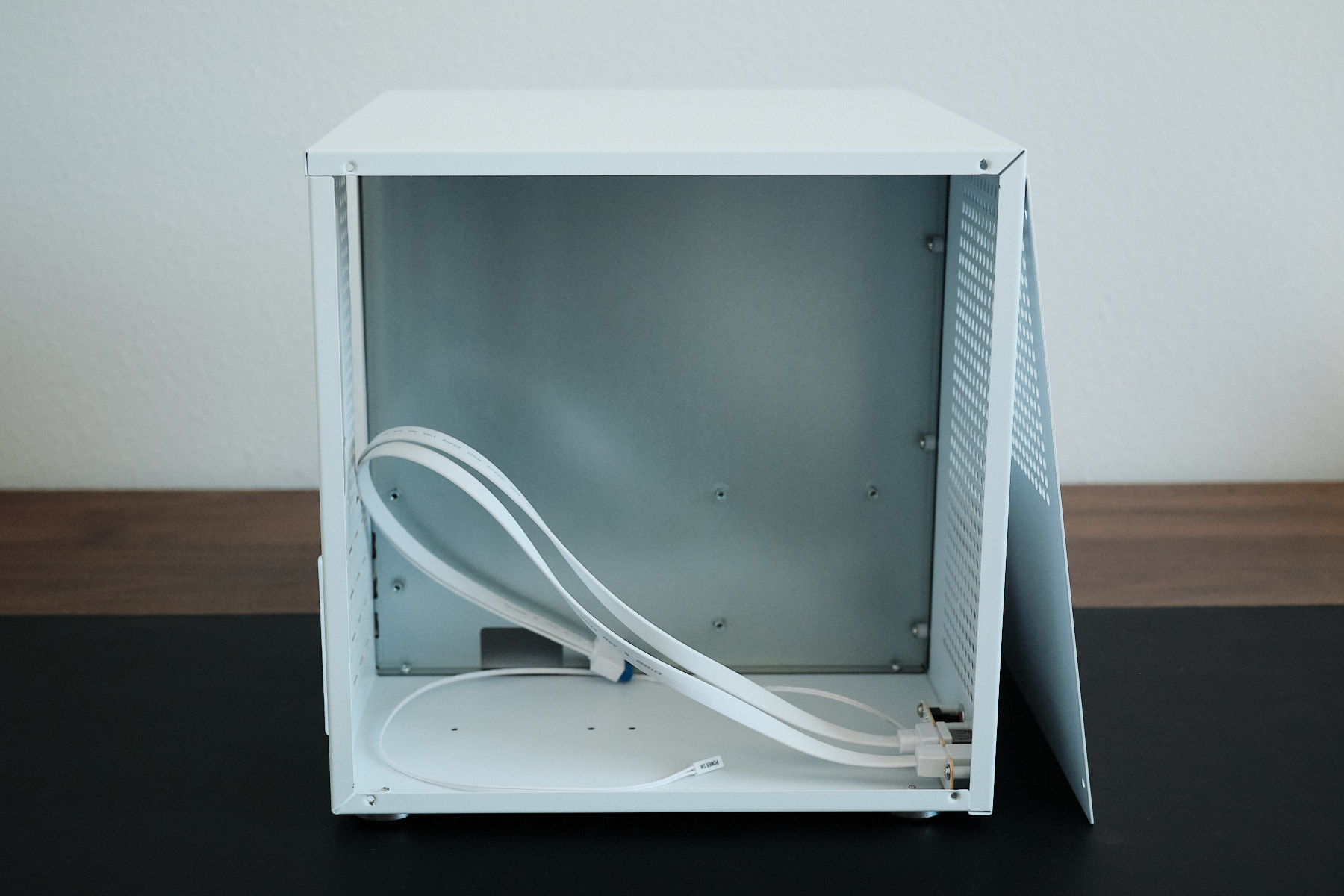 Interior of the Sagittarius NAS case viewed from the right side, showing the bare motherboard area and front I/O cables with no cable management tie-down points